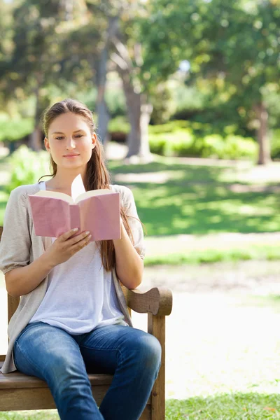 Woman reading a book on a park bench — Stock Photo, Image