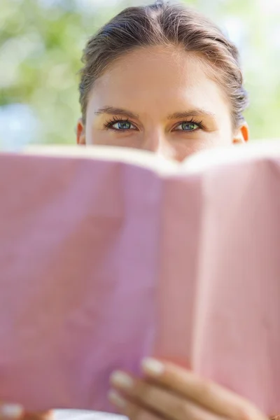 Γυναίκα, κρύβοντας το πρόσωπό της πίσω από ένα βιβλίο στο πάρκο — Φωτογραφία Αρχείου