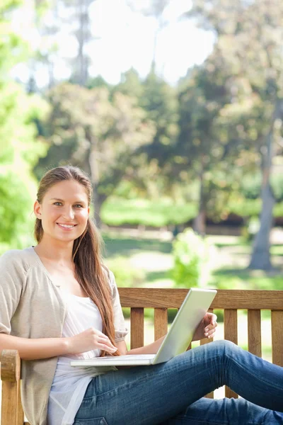 Uśmiechający się z jej notatnik na ławce w parku — Zdjęcie stockowe