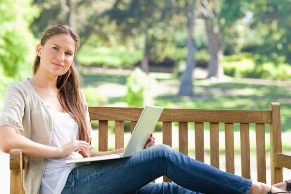 Kobieta z jej laptopa na ławce w parku — Zdjęcie stockowe