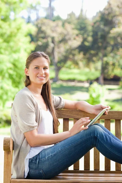 Side view of a smiling woman with a tablet computer on a park be — Stock Photo, Image