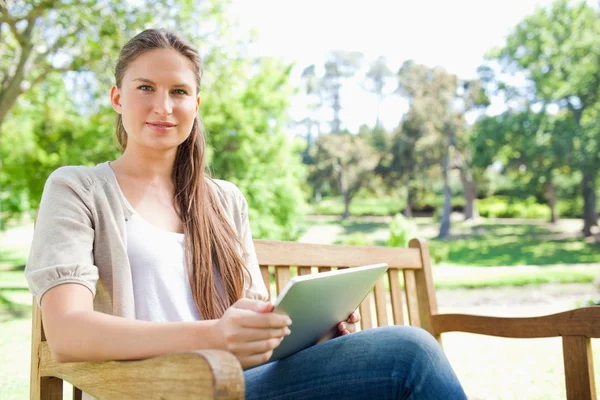 女子坐在公园的长椅上，与她的平板电脑 — 图库照片