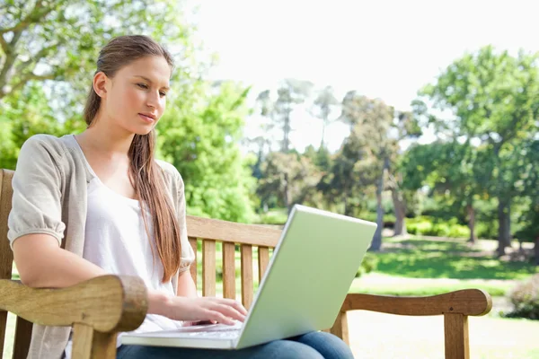 Kobieta z laptopa na ławce w parku — Zdjęcie stockowe