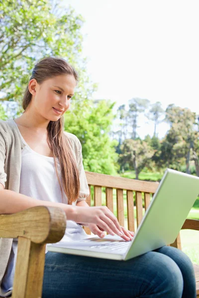 Kobieta na ławce w parku z jej laptop — Zdjęcie stockowe