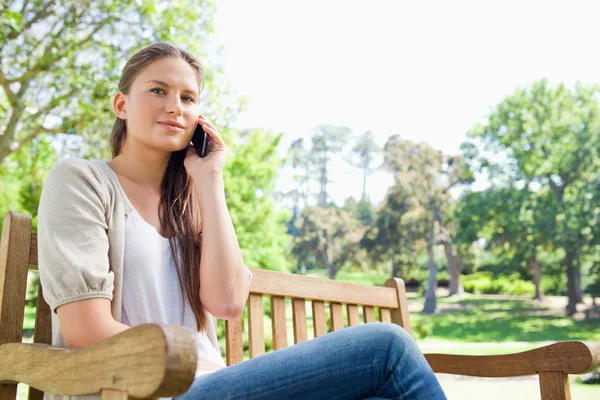 Woman on her phone on a park bench — Stock Photo, Image