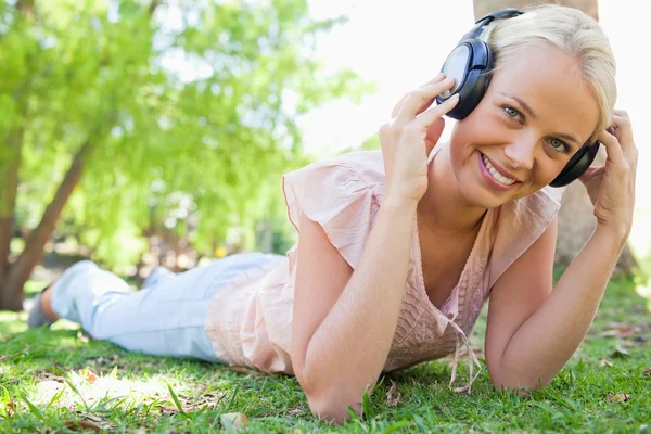 Leende kvinna njuter musik på gräset — Stockfoto