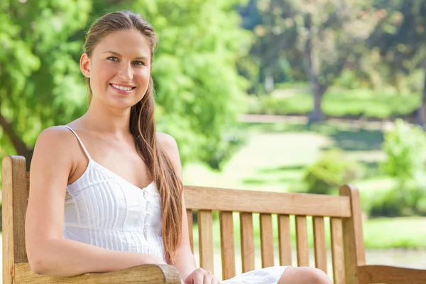 Usmívající se žena na lavičce v parku — Stock fotografie