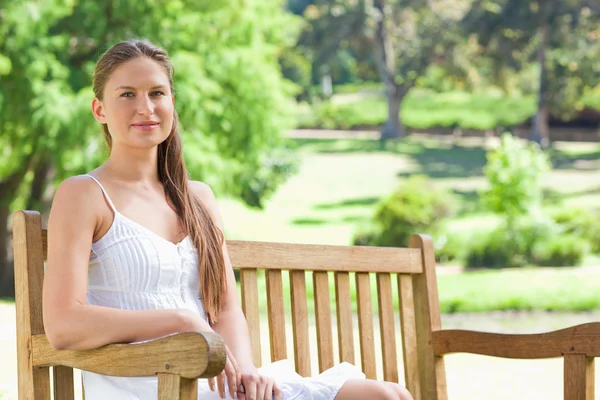 Vrouw zittend op een bank in het park — Stockfoto