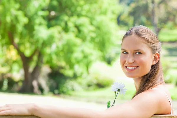 Vue latérale d'une femme souriante avec une fleur — Photo