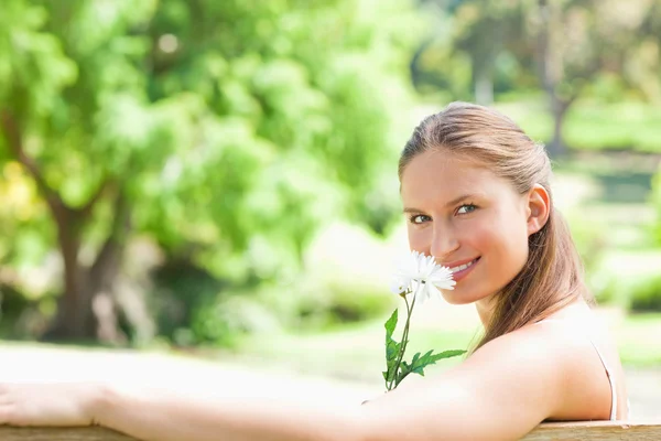 Seitenansicht einer lächelnden Frau, die eine Blume riecht — Stockfoto