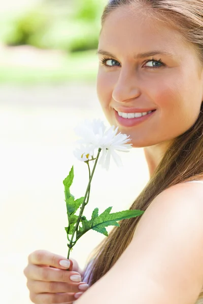 Крупным планом улыбающейся женщины, нюхающей цветок — стоковое фото