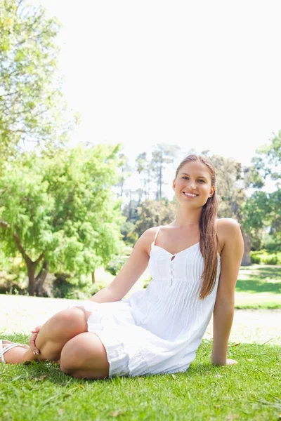 Mulher sorridente no parque sentado no gramado — Fotografia de Stock