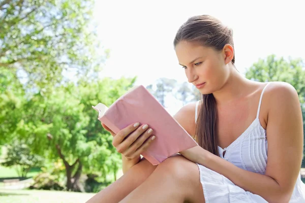 Sidovy av en kvinna läser en roman i parken — Stockfoto