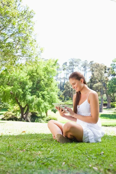 Side view of a smiling woman on the lawn with a tablet computer — Stock Photo, Image