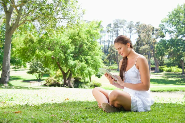 Вид збоку жінки на газоні зі своїм планшетним комп'ютером — стокове фото