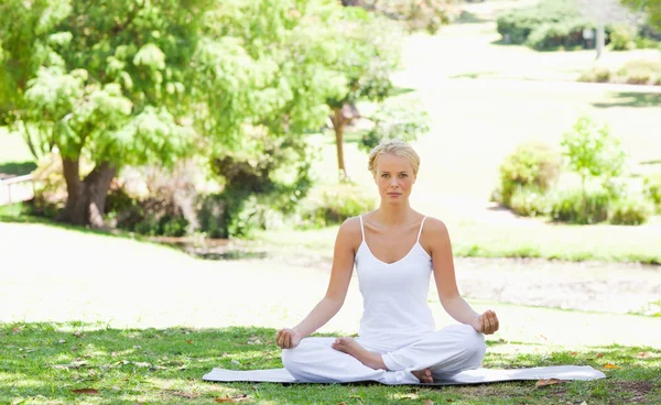 Femme assise dans une position de yoga dans le parc — Photo
