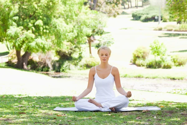 Woman sitting in a yoga position on the lawn — Stock Photo, Image