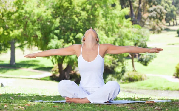 Žena na trávníku dělá cvičení jógy — Stock fotografie