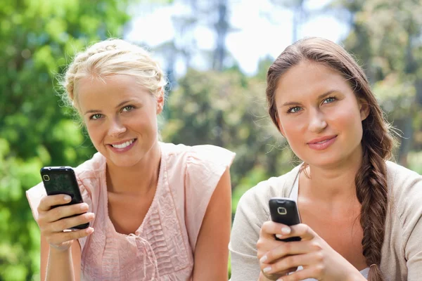 Vrienden met hun mobiele telefoons in het park — Stockfoto