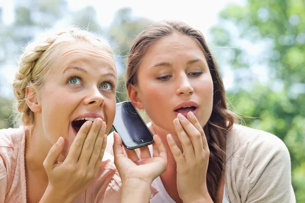 Curious friends listening to phone call in the park — Stock Photo, Image