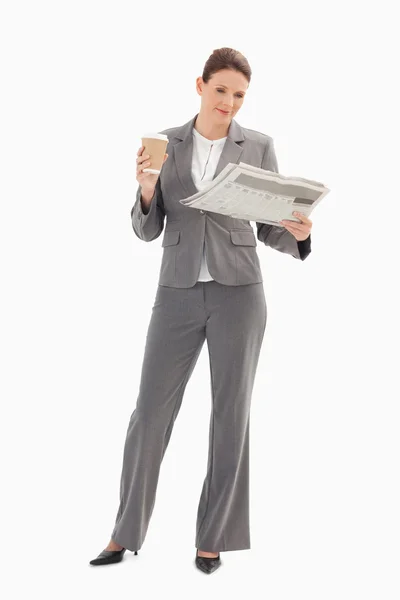 Geschäftsfrau liest Zeitung und hält Kaffee — Stockfoto