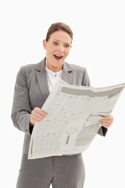 Surprised businesswoman standing reading the newspaper — Stock Photo, Image