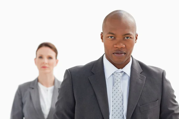 Businessman staring at camera with businesswoman behind him — Stock Photo, Image