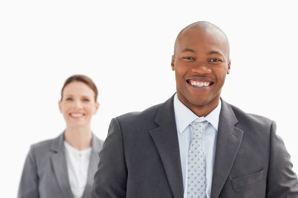 Hombre de negocios sonriente con una mujer de negocios sonriente de pie detrás — Foto de Stock