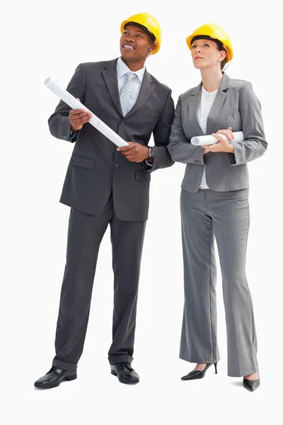 Businessman and woman with notes and hard hats — Stock Photo, Image