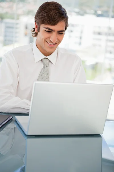 Lachende jonge zakenman is op zijn laptop — Stockfoto