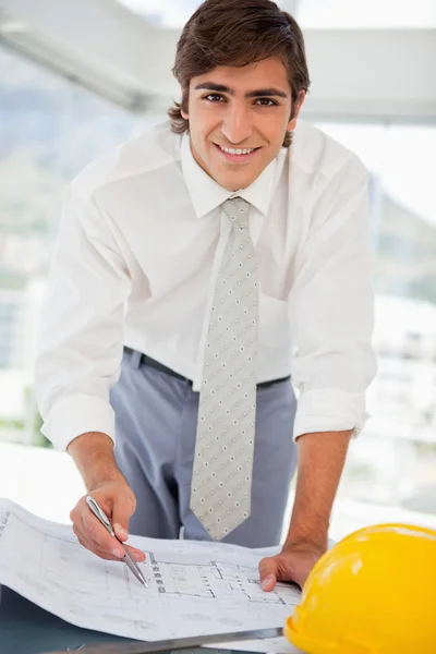Smiling businessman with blueprints and a hard hat — Stock Photo, Image