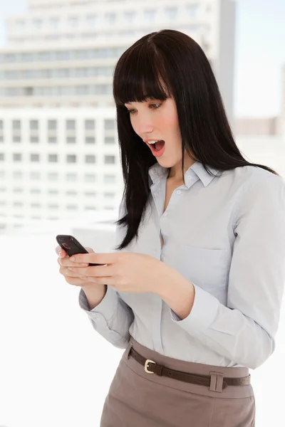 Schockierte Frau liest Text aus ihrem Handy — Stockfoto