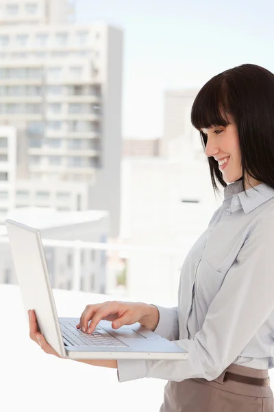 Eine lächelnde Frau benutzt ihren Laptop bei der Arbeit — Stockfoto