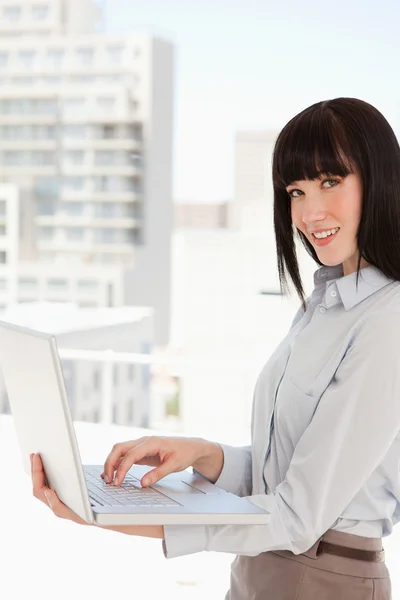 A woman looking at the camera while holding a laptop — Stock Photo, Image