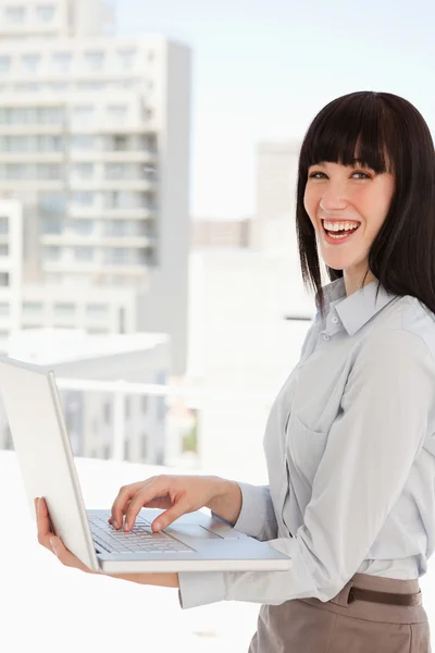 En skrattande affärskvinna med en laptop i hennes händer — Stockfoto