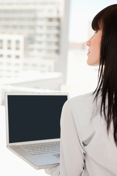 Женщина в офисе с ноутбуком в руке — стоковое фото