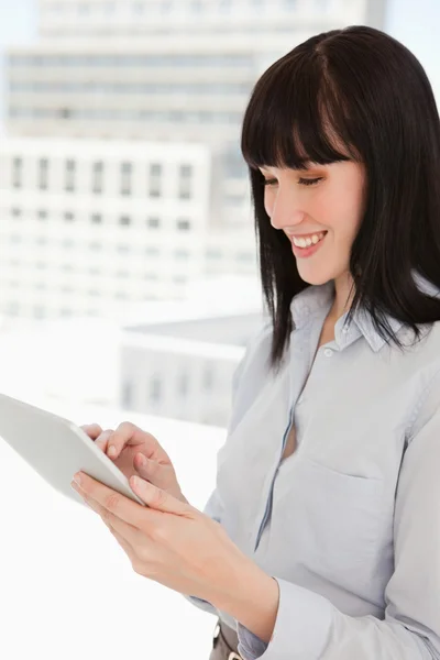 Uma mulher feliz usando seu tablet pc em seu escritório — Fotografia de Stock