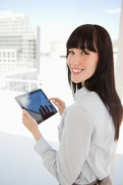 Frau blickt in die Kamera, während sie einen Tablet-PC in der Hand hält — Stockfoto