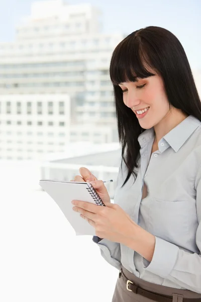 A smiling business woman writing down some notes — Stock Photo, Image