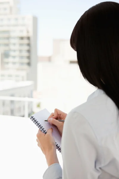 Eine Frau beginnt, sich auf ihren Notizblock zu schreiben — Stockfoto