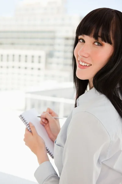 A woman looking back at the camera as she holds a notepad — Stock Photo, Image