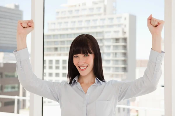 En leende glad kvinna med armarna upp precis ovanför hennes huvud — Stockfoto