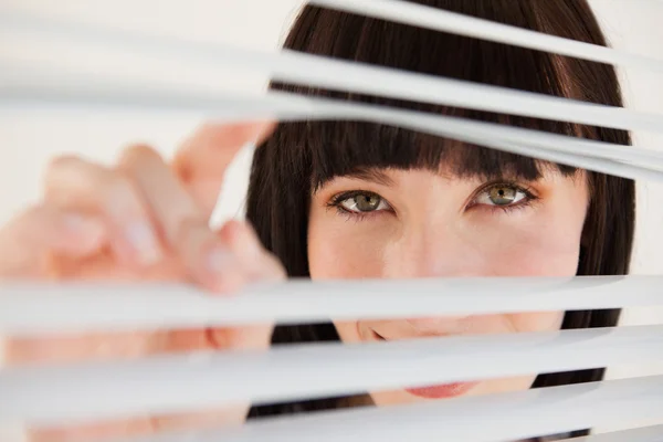 A woman moving open some blinds in front of her — Stock Photo, Image