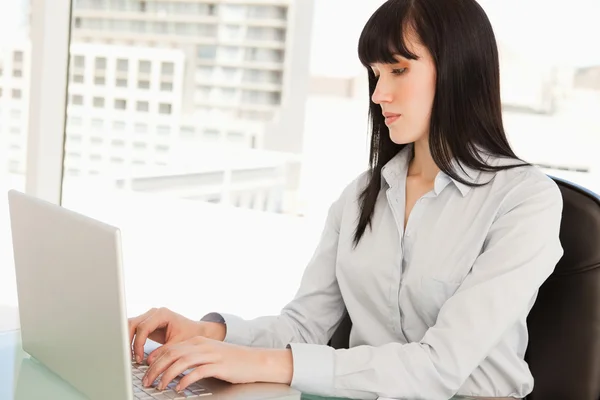 Una mujer en su computadora portátil escribiendo —  Fotos de Stock