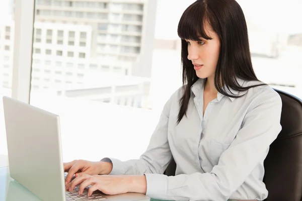 Una mujer mirando la pantalla de su computadora portátil mientras escribe —  Fotos de Stock