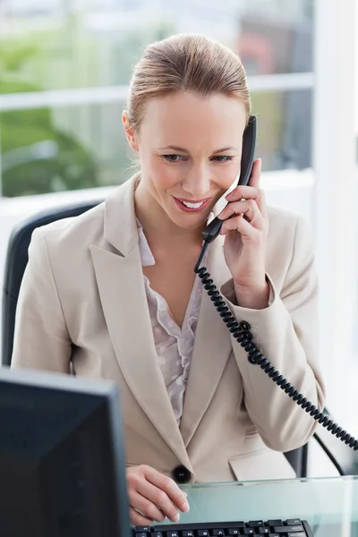 Женщина в костюме разговаривает по телефону в офисе — стоковое фото