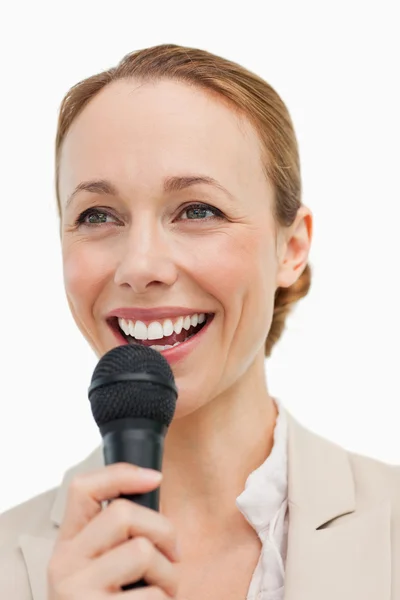 Enthusiastic woman in a suit speaking with a microphone — Stock Photo, Image