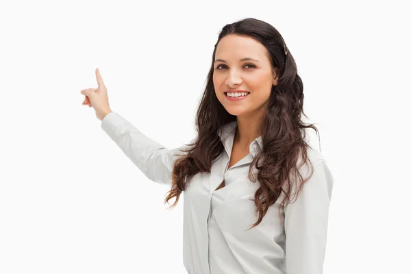 Portrait of a smiling brunette pointing in her back — Stock Photo, Image