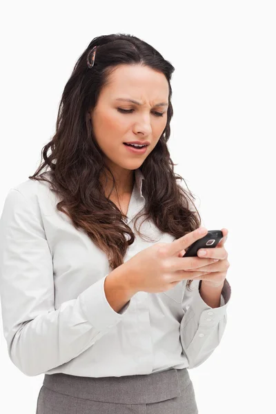 Brunette grimassen terwijl het zoeken van haar SMS-bericht — Stockfoto