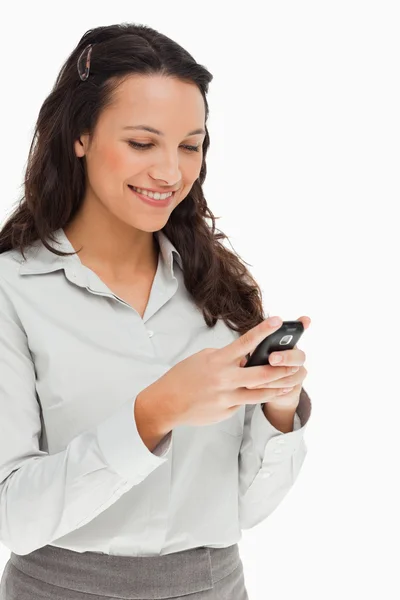 Brünette lächelt, während sie ihr Handy benutzt — Stockfoto